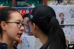 Dua perempuan sedang berbincang di depan majalah yang menampilkan gambar Presiden Xi Jinping dan idola remaja, Lu han, di Beijing, 22 Oktober 2017.