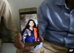 Abdul Aziz Sheikh, center, father of Sabika Sheikh, a victim of a shooting at a Texas high school, shows a picture of his daughter in Karachi, Pakistan, May 19, 2018.