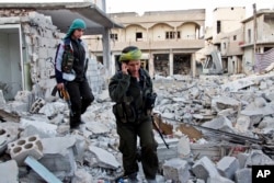 FILE - Kurdish female fighters move to another secured point in the contested zone of Kobani, Syria, on Nov. 19, 2014.