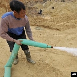 A Chinese worker waters the site of a rare earth metals mine at Nancheng county, Jiangxi province, December 29, 2010.