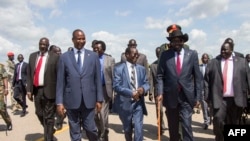 Le président du Soudan du Sud Salva Kiir (C/R) marche avec des responsables sur le tarmac de l'aéroport international de Juba le 13 septembre 2018, après son retour de la capitale éthiopienne Addis-Abeba.