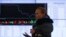 A woman walks past an information screen inside the office of the Moscow Exchange on March 14, 2014. Russian stock indexes have plunged in recent months.