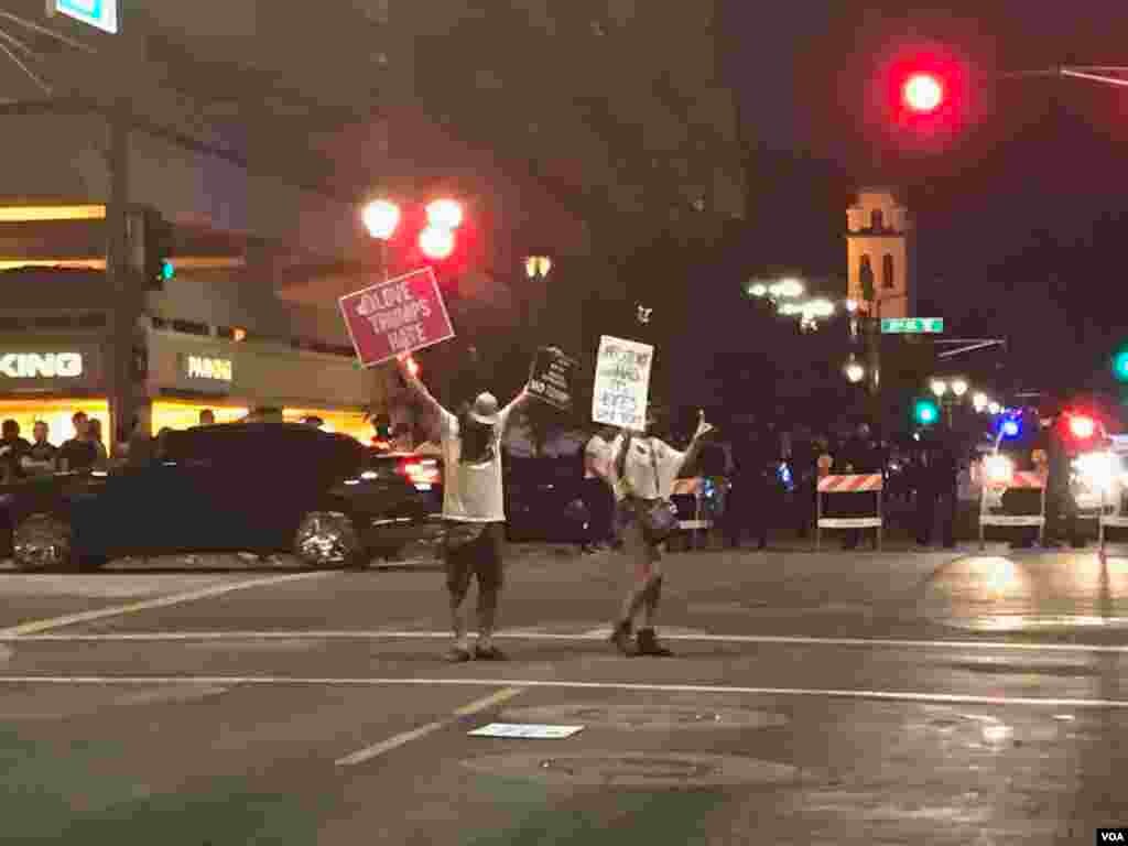 Protesters stand in the middle of the street as police officers in riot gear keep launching pepper bullets after clashes with demonstrators in Phoenix, Az, Aug. 22, 2017. (Photo: Celia Mendoza / VOA) 