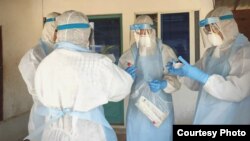 មន្ត្រីសុខាភិបាលមួយក្រុមស្ថិតក្នុងសម្លៀកបំពាក់តាមក្បួនខ្នាត ខណៈពួកគេកំពុងបំពេញកិច្ចការគ្រប់គ្រង និងទប់ទល់ការឆ្លងរាលដាលនៃវីរុសកូរ៉ូណានៅកម្ពុជា។ (រូបថតដោយ៖ នាយកដ្ឋានប្រយុទ្ធនឹងជំងឺឆ្លង CDC)