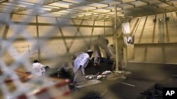 Afghan detainees, seen through a mesh wire fence, prepare for noon prayers inside the Parwan detention facility near Bagram Air Field in Afghanistan, March 23, 2011.