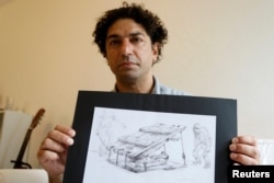 Exiled Syrian artist Najah al-Bukai poses with a ball-pen drawing that stems from the haunting memories of the torture Bukai says he went through and witnessed when imprisoned twice in Syrian government jails, in Yerres, near Paris, Sept. 13, 2018.