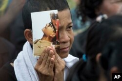 A mourner holds a portrait of the late King Bhumibol Adulyadej during his funeral procession and royal cremation ceremony in Bangkok, Thailand, Oct. 26, 2017.