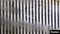 Dünya Ticarət Mərkəzində təyyarə vurulan nöqtədən yuxarıda ilişib qalmış adamlar pəncərədən baxır.