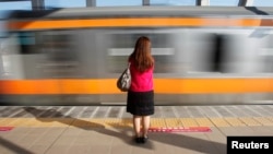 FILE - A woman waits to board a 'women only' passenger train during morning rush hours in Tokyo. The study examined responses from more than 9,600 women employees, submitted by mail or online.
