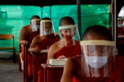 Biksu Buddha muda dengan masker, duduk menjaga jarak sosial berpartisipasi dalam kelas agama di Institut Pendidikan Molilokayaram di Bangkok, Thailand, Rabu, 15 April 2020. (Foto: AP)