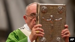 FILE - Pope Francis hoists the Gospel book as he celebrates a mass in St. Peter's Basilica at the Vatican, Oct. 5, 2014, to open the extraordinary Synod on the family.