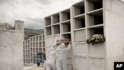 Pekerja pemakaman menempatkan peti mati berisi jenazah Jose de Arimateia, 65, yang meninggal karena komplikasi terkait Covid-19, ke dalam ceruk di pemakaman kota di Nova Iguacu, Brazil, 24 September 2020. (Foto: AP/Silvia Izquierdo )