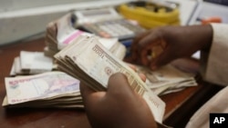 Seorang pegawai pertukaran uang menghitung mata uang naira di Lagos, Nigeria.