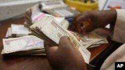 FILE - a money changer counts Nigerian naira currency at a bureau de change in Lagos, Nigeria, Oct. 20, 2015.