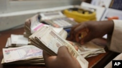 FILE - a money changer counts Nigerian naira currency at a bureau de change in Lagos, Nigeria, Oct. 20, 2015. A Nigerian Federal High Court is ordering governments going back to 1999 to account for hundreds of millions of dollars that were returned by foreign governments because the funds were deemed to have been looted from the Nigerian state.