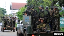 FILE - Government soldiers are seen onboard military vehicles driving along the main road of Amai Pakpak as the assault continues against insurgents from the Maute group, who have taken over large parts of Marawi City, Philippines, June 13, 2017.