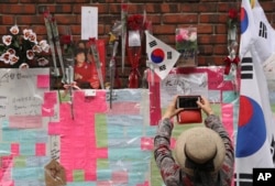 A supporter of former South Korean President Park Geun-hye takes photo with smartphone in front of the wall of Park's private home in Seoul, March 27, 2017.