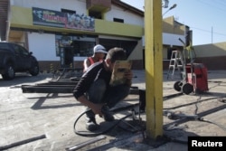 Workers repair the fence of a looted supermarket in Puerto Ordaz, Venezuela, Jan. 9, 2018.