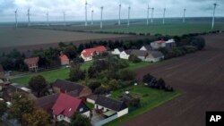 Wind turbines turn near the village of Feldheim, rear left, near Treuenbrietzen, Germany, Wednesday, Sept. 28, 2022. (AP Photo/Michael Sohn)