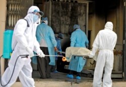 Municipal workers in protective gear carry the body of a woman who died of the coronavirus disease (COVID-19), to a crematorium in Ahmedabad, India, April 17, 2020.