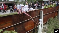 School children hand out food to a Rohingya young girl from outside the fence of a temporary shelter in Aceh province, Indonesia, May 21, 2015. (FILE PHOTO)