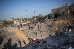 FILE - Palestinians sit amid the rubble of their destroyed house following overnight Israeli missile strikes, in the town of Khan Younis, southern Gaza Strip, Nov. 14, 2019.