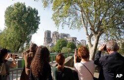 People take pictures of Notre Dame in Paris, April 19, 2019. Rebuilding the 800-year-old cathedral devastated by fire this week will cost billions of dollars as architects, historians and artisans work to preserve the medieval landmark.