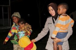 Seorang petugas polisi mengevakuasi warga Papua setelah bentrokan antara aparat keamanan dan pemberontak separatis, di Mimika, Papua, 8 Maret 2020. (Foto: Antara/Sevianto Pakiding via REUTERS)