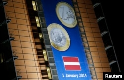 FILE - A banner showing a Latvian Euro coin is seen on the facade of the European Commission headquarters during a European Union leaders summit in Brussels, Dec. 20, 2013.