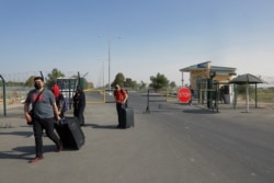 People cross a police checkpoint two kilometers from Friendship Bridge, which separates Uzbekistan and Afghanistan, near Termez, Uzbekistan, Aug. 14, 2021.