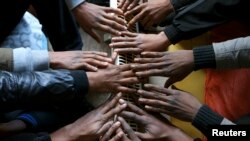 Des demandeurs d'asile de la Guinée, du Libéria et de la Sierra Leone se réchauffent près d'un radiateur électrique dans une maison abandonnée à Bruxelles le 7 Janvier 2015. (REUTERS/Francois Lenoir)