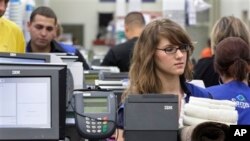 Cashier Jillian Capko, right, checks merchandise at a Sam's Club store, Rogers, Ark., June 2011 file photo.