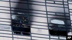 A firefighter looks out from the window of a damaged apartment in Trump Tower, in New York, April 7, 2018. 