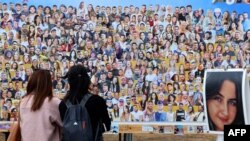 Pengunjung warga Israel memperhatikan foto-foto orang-orang yang disandera atau terbunuh dalam serangan oleh Hamas terhadap festival musik Supernova pada 7 Oktober 2023, dekat Kibbutz Rein di selatan Israel, 10 April 2024. (Foto: Jack Guez/AFP)