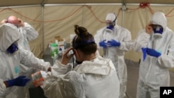In this photo provided by the New South Wales Police, investigators in protective gear prepare to board the Ruby Princess cruise ship in Wollongong, Australia, April 8, 2020. 