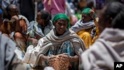 Sur cette photo du samedi 8 mai 2021, une femme éthiopienne ramasse des grains de blé après sa distribution par la Société de Secours du Tigré dans la ville d'Agula, dans la région du Tigré au nord de l'Éthiopie.