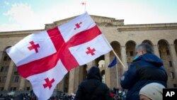 FILE - Georgian opposition supporters demanding new parliamentary elections rally in Tbilisi, Georgia, Feb. 23, 2021.