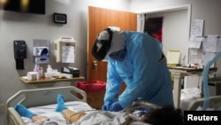 Christopher Peter, 32, seorang spesialis pernapasan, memeriksa pasien saat profesional medis merawat orang yang terinfeksi Covid-19 di United Memorial Medical Center di Houston, Texas, AS, 12 November 2020. (Foto: Reuters)