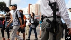 Andrew Clements, right, a licensed gun owner, open carrying a high-velocity rifle, demonstrates on Guadalupe St., next to the University of Texas, in Austin, Texas, Aug. 24, 2016.
