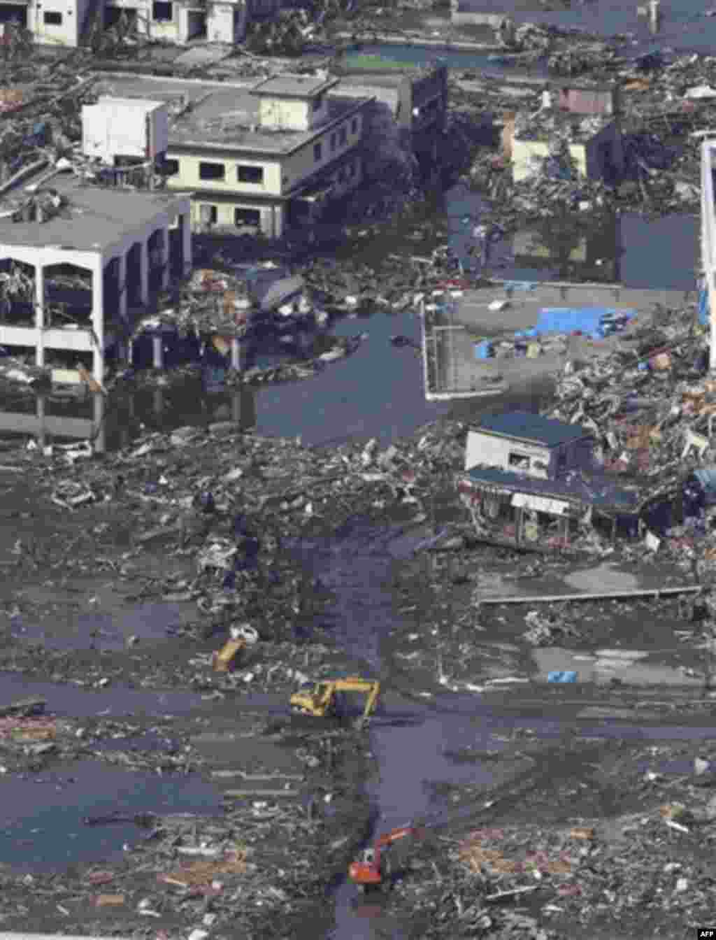 Excavators work to make temporary paths at a debris-covered area of Rikuzentakata, northern Japan, Monday, March 14, 2011, three days after a powerful earthquake-triggered tsunami hit the country's east coast. (AP Photo/The Yomiuri Shimbun, Atsushi Takeda