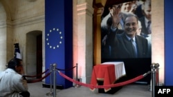 A man looks at the coffin of former French President Jacques Chirac lying in state during a memorial ceremony at the Saint-Louis-des-Invalides cathedral at the Invalides memorial complex in central Paris, Sept. 29, 2019.