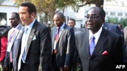 Botswana President Ian Khama (L) walks alongside Zimbabwe President Robert Mugabe (R) during a lunch break at the SADC summit in Maputo, June 15, 2013. 