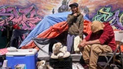 Lucio Lopez, left, talks with friends as he stands in a tent that is part of a homeless encampment in the Queens borough of New York, Tuesday, April 13, 2021.