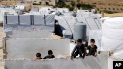 FILE - Displaced Syrian children climb a concrete wall at a refugee camp in the eastern Lebanese border town of Arsal, Lebanon, Aug. 5, 2019. 