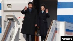 Presiden China Xi Jinping (kiri) dan ibu negara Peng Liyuan melambaikan tangannya setibanya di bandara Vnukovo, Moskow (22/3).