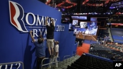 Workers place a Romney-Ryan campaign sign inside of the Tampa Bay Times Forum at the Republican National Convention in Tampa, Florida, Sunday, Aug. 26, 2012. 