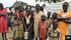 Angelina Wicyote, a 39-year-old mother of eight and resident of the camp, center, stands with her family during a visit of UNCHR High Commissioner in Bentiu, South Sudan Sunday, June 18, 2017. (AP Photo/Sam Mednick)