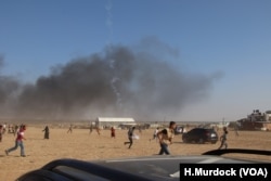 People run as a tear gas canister falls far beyond the front line of a protest in Gaza, May 15, 2018.