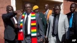 Presiden Zimbabwe Emmerson Mnangagwa (kedua dari kiri) meninggalkan TPS setelah memberikan suara dalam Pilpres di kota Kwekwe, Senin (30/7). 