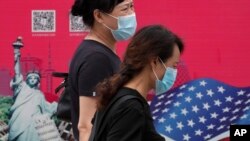 北京街头行人走过有着美国国旗和纽约自由女神画像的广告牌。（2020年8月6日）